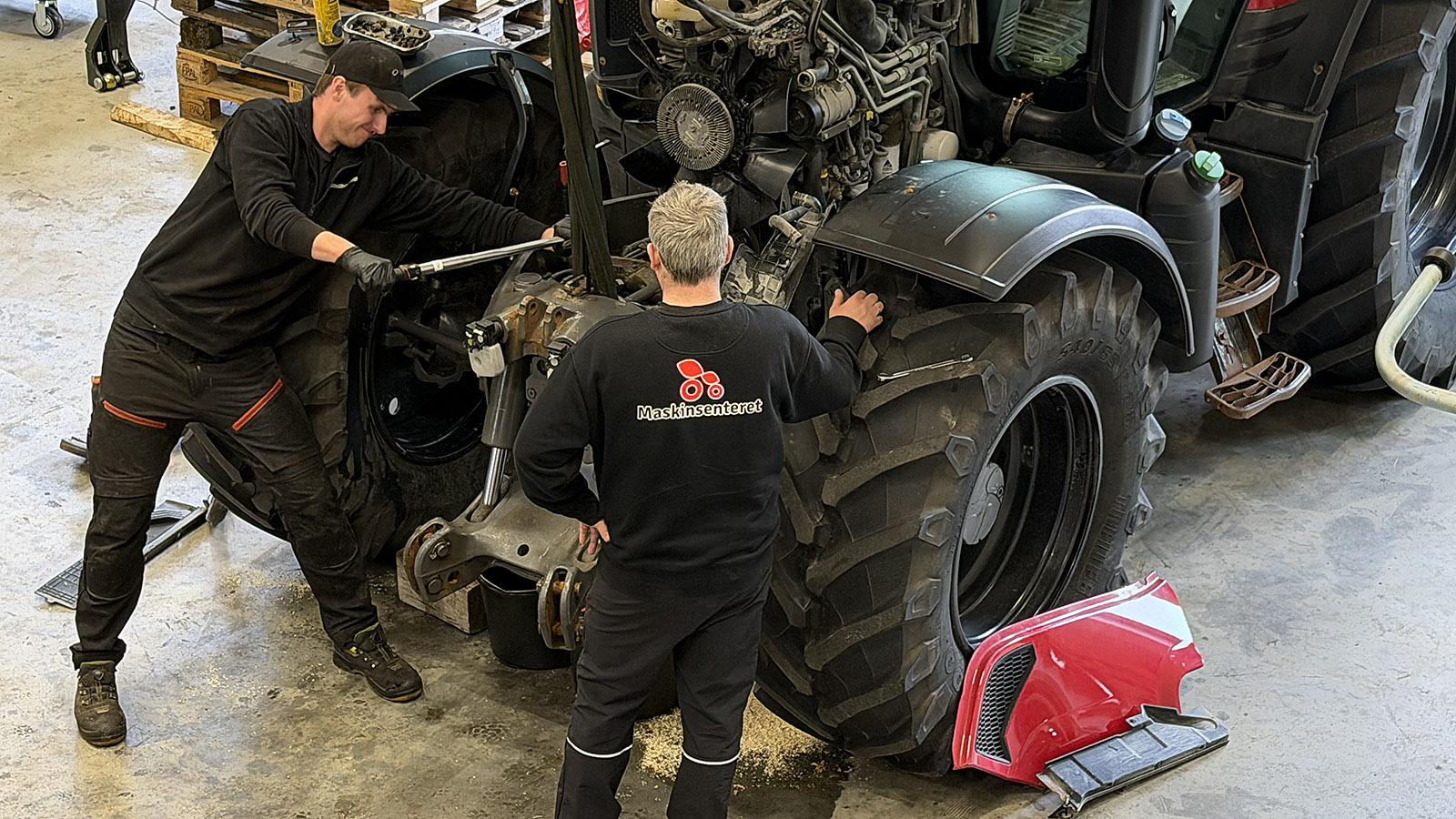 Morten Ommedal ettermonterer front-PTO på en Valtra. Verksmester Leif Erling Avedal følger med på arbeidet. Foto: Lars Ovlien. 